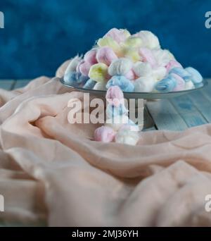 Colored cotton balls in various containers on a blue background Stock Photo
