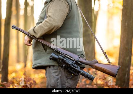 Hunter or ranger with a professional, nightvision hunting gun and hunting form to hunt in an autumn forest, hunting concept Stock Photo