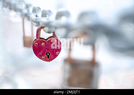 Red heart shaped lock hangs from chain, wedding custom, concept of love and health Stock Photo