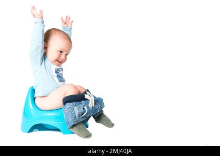 Happy one year old boy having fun on chamber pot, isolated over white background Stock Photo