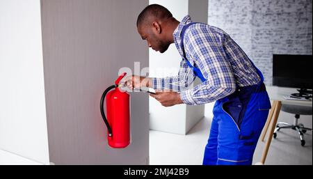 Male Professional Checking A Fire Extinguisher Security Inspection Stock Photo
