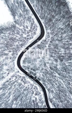 Winding country road leads through a forest in the Swabian Alb, there is snow, drone photo, Gutenberger Steige, Lenningen-Gutenberg Stock Photo