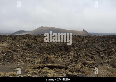 Old volcanic cone surrounded by lava in Tinajo, Lanzarote Stock Photo