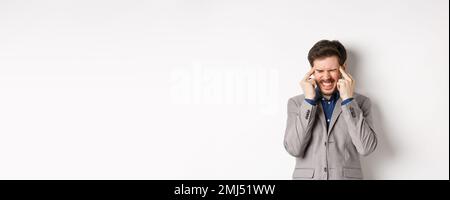 Image of frustrated man trying to think, cant remember something, touching head temples and squinting with tensed grimace, brainstorming, searching Stock Photo