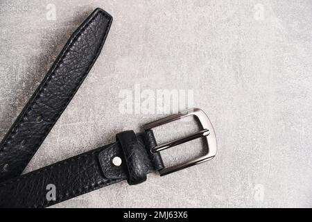Black men leather belt with metal badge gray concrete background Stock Photo