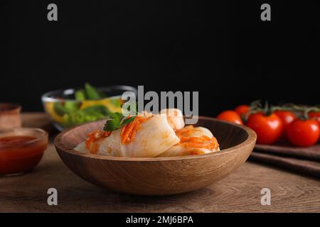Delicious cabbage rolls served on wooden table against black background Stock Photo