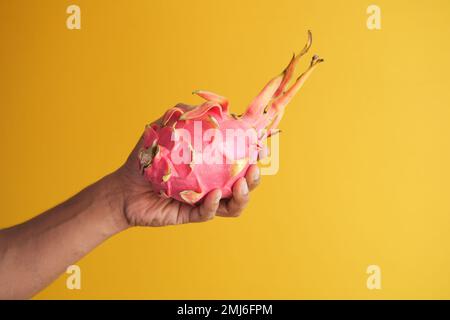 men holding a dragon fruit on yellow background  Stock Photo