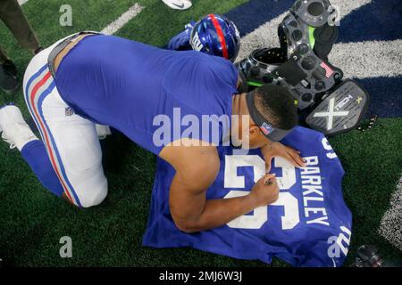 New York Giants running back Saquon Barkley (26) signs his jersey