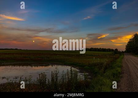 The moon rising over a farmer's field in northern Wisconsin. Stock Photo