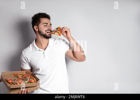 Handsome man eating pizza on white background, space for text Stock Photo