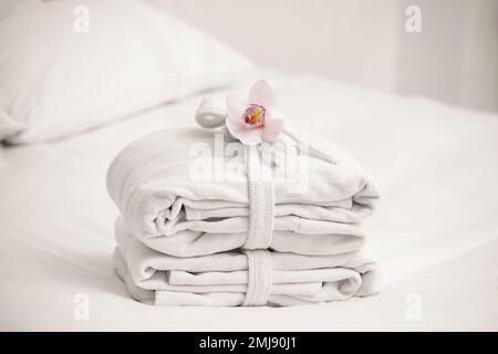 Clean folded bathrobes on bed in room Stock Photo