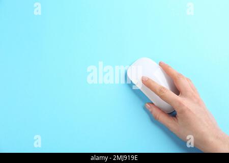 Woman using modern wireless optical mouse on light blue background, top view. Space for text Stock Photo