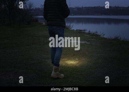 Man with flashlight walking near river, closeup Stock Photo