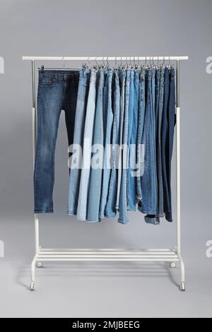 Rack with different jeans on grey background Stock Photo