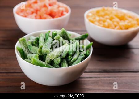 Different tasty frozen vegetables on wooden table Stock Photo