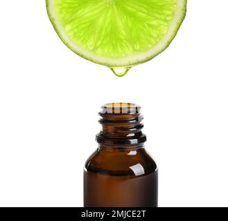 Essential oil dripping from lime slice into bottle isolated on white Stock Photo