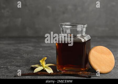 Aromatic homemade vanilla extract on grey table Stock Photo