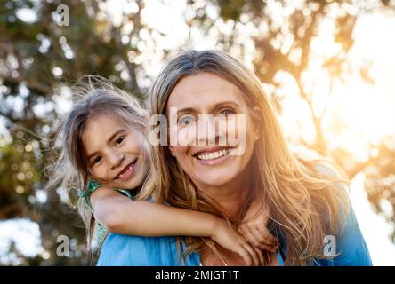 My daughter is my everything. Portrait of a happy mother and daughter enjoying a piggyback ride outdoors. Stock Photo