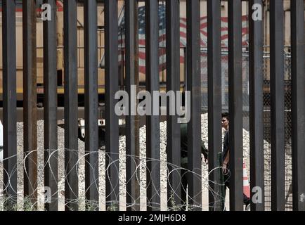 Three migrants who had managed to evade National Guard and cross the Rio  Grande onto U.S. territory wait for Border Patrol along a wall set back  from the geographical border, in El