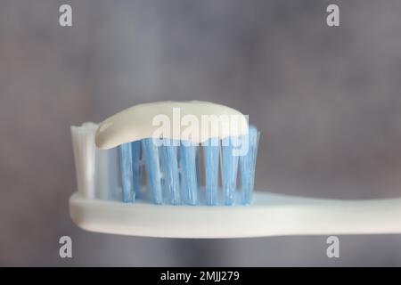 Close up of toothpaste on toothbrush on gray background. Stock Photo