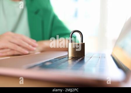 Laptop computer with padlock on office desk and business woman or manager in background. Stock Photo