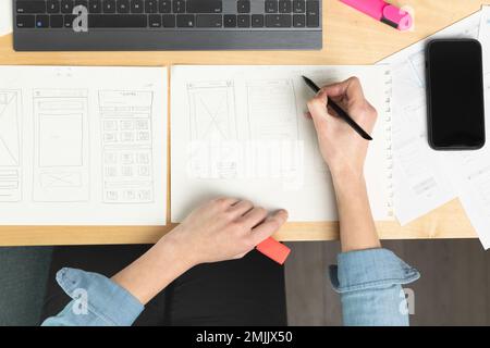 Sketch of wireframe for website. Women designer working on a mobile application, drawing on paper. Stock Photo