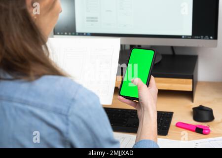Sketch of wireframe for website. Women designer working on a mobile application, holding in hand phone with green screen Stock Photo