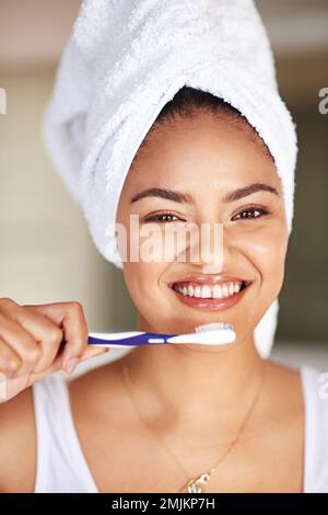 Got to get them white and bright. Portrait of a young woman brushing her teeth in the bathroom. Stock Photo