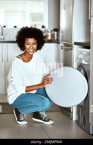 My little laundry helper. Portrait of a young woman doing laundry at home. Stock Photo