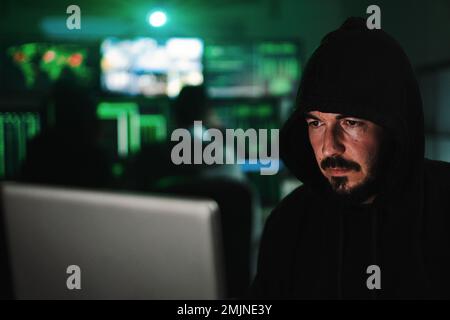 Close up portrait of one hacker looking the screen of a laptop computer, typing the code to breack the security of the firewall on internet. High quality photo Stock Photo
