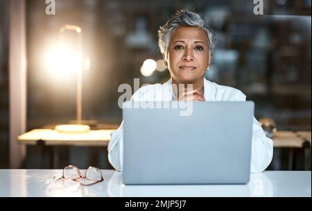 Doctor, laptop and portrait of senior woman in hospital working late or overtime on email, telehealth or research. Elderly, healthcare and confident Stock Photo