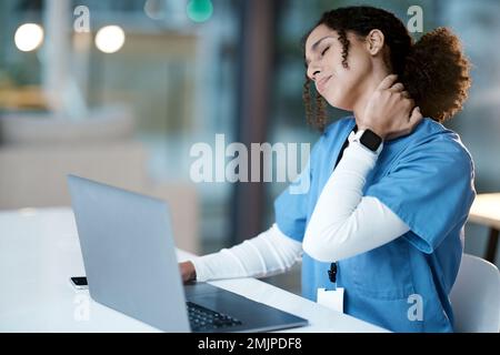 Doctor, laptop and neck pain at night in agony, stressed or burnout by desk at the hospital. Woman medical professional suffering from painful injury Stock Photo