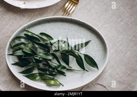 Rustic wedding table seting with vintage plates, green and white eucalyptus garland, gold utensils. Boho style. Table set for an event, party, date or Stock Photo
