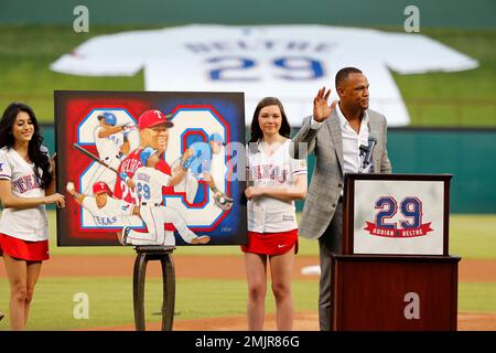 Retired Texas Rangers player, Adrian Beltre (left) signals to the crowd  while sitting with his family during a ceremony where his Texas Rangers  jersey was retired before the second baseball game of