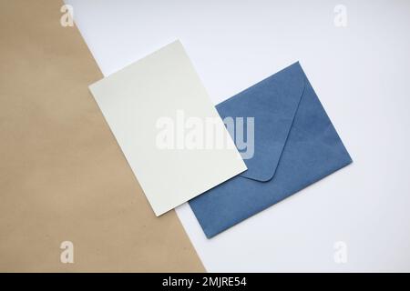 postcard mockup vertical, on white and brown background blue closed envelope and white sheet vertically Stock Photo