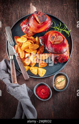 Homemade roasted pork knuckle served with fries and ketchup. Roasted pork knuckle with potatoes. Stock Photo