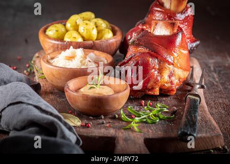 Cripsy roasted pork knuckle served with sauerkraut and potatoes. Roasted Schweinshaxe with sauerkraut. Stock Photo