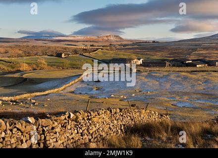 Winter afternoon view of Ribblehead Viaduct and a distant Pen-y-ghent peak, with Gunnerfleet Farm centre, near Ingleton, Yorkshire Dales National Park Stock Photo
