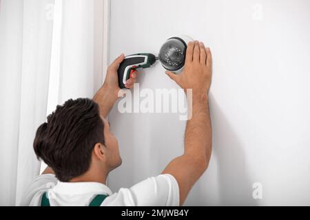 Technician installing CCTV camera on wall indoors Stock Photo