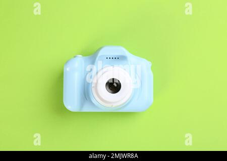 Light blue toy camera on green background, top view Stock Photo