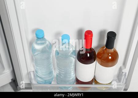 Bottles of water and wine on shelf in refrigerator Stock Photo