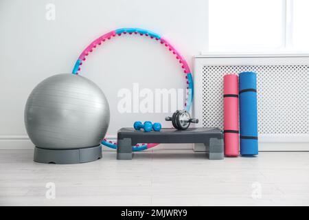 Different sports equipment near white wall in gym Stock Photo