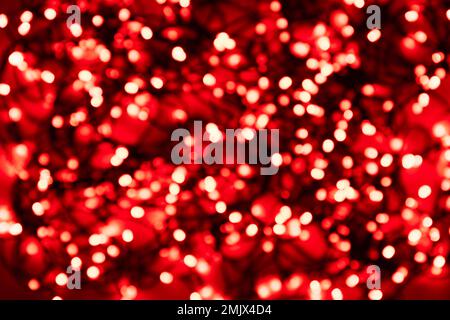 Blurred tangled wire garlands with red light bulbs on a red background Stock Photo