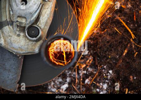 Angle grinder machine works with bright sparks stream, close up photo with selective focus Stock Photo