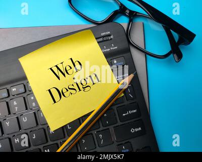 Pencil and keyboard with the word WEB DESIGN on blue background. Stock Photo