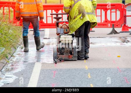 Builder using petrol powered road saw with dimond blade to cut asphalte road surface Stock Photo