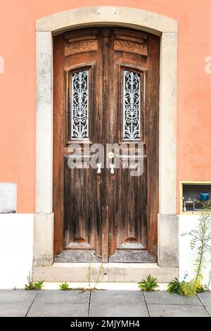 Old wooden door with wrought iron door knockers on pink facade in Lisbon, Portugal Stock Photo