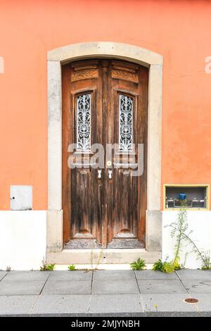 Old wooden door with wrought iron door knockers on pink facade in Lisbon, Portugal Stock Photo