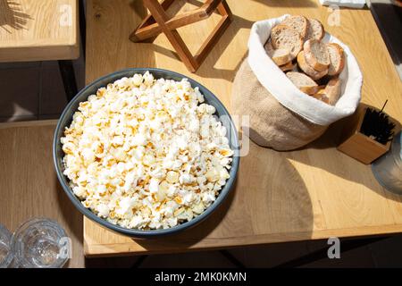 popcorn cheese in large bowl cup closeup horizontal top view with basket of sliced breads