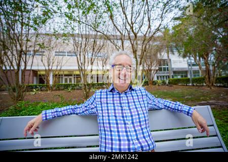 Happy senior old man sitting on a park bench Stock Photo